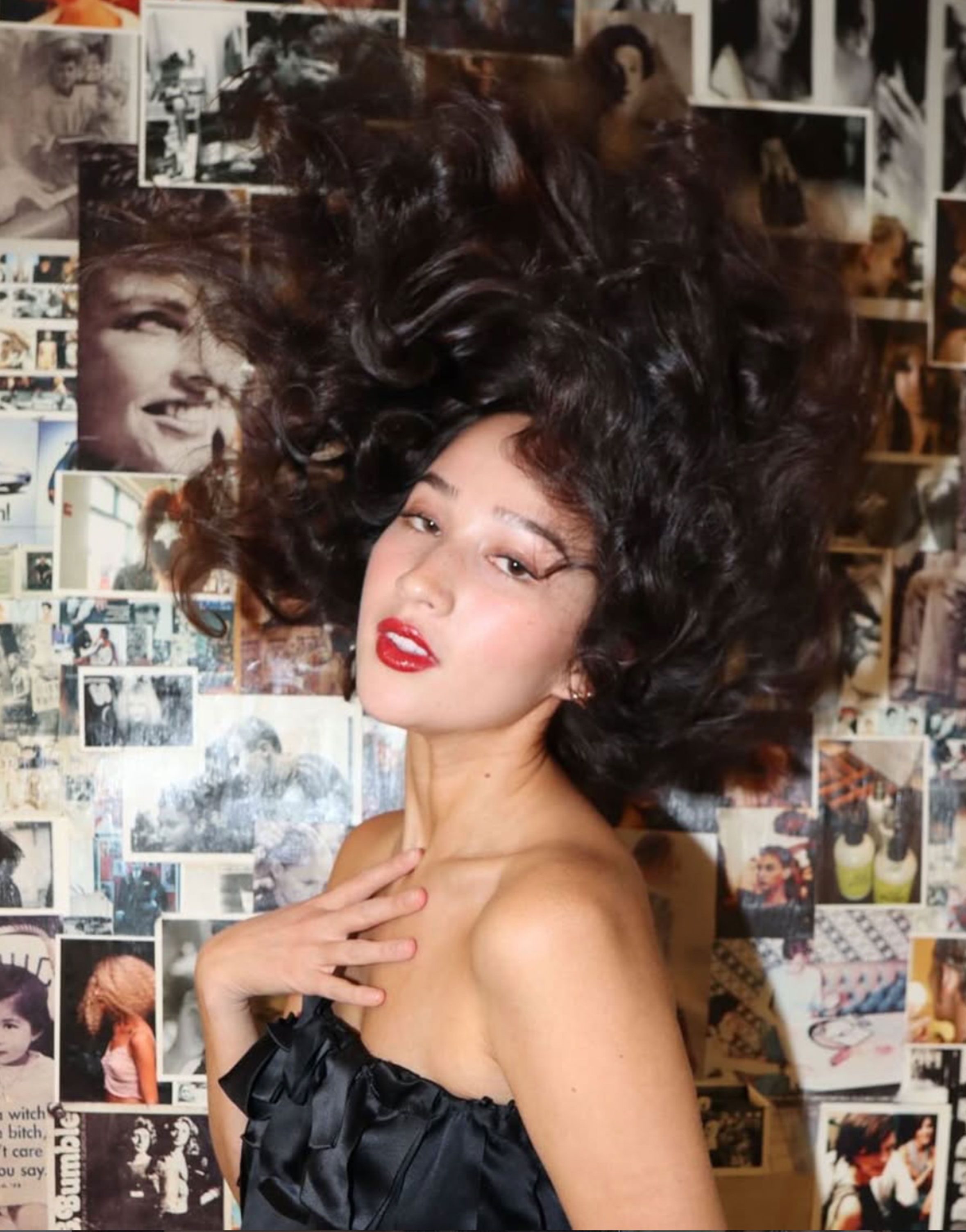 Editorial hair by David Anthony Hiller — voluminous curled hair in motion against a photo-collage wall.