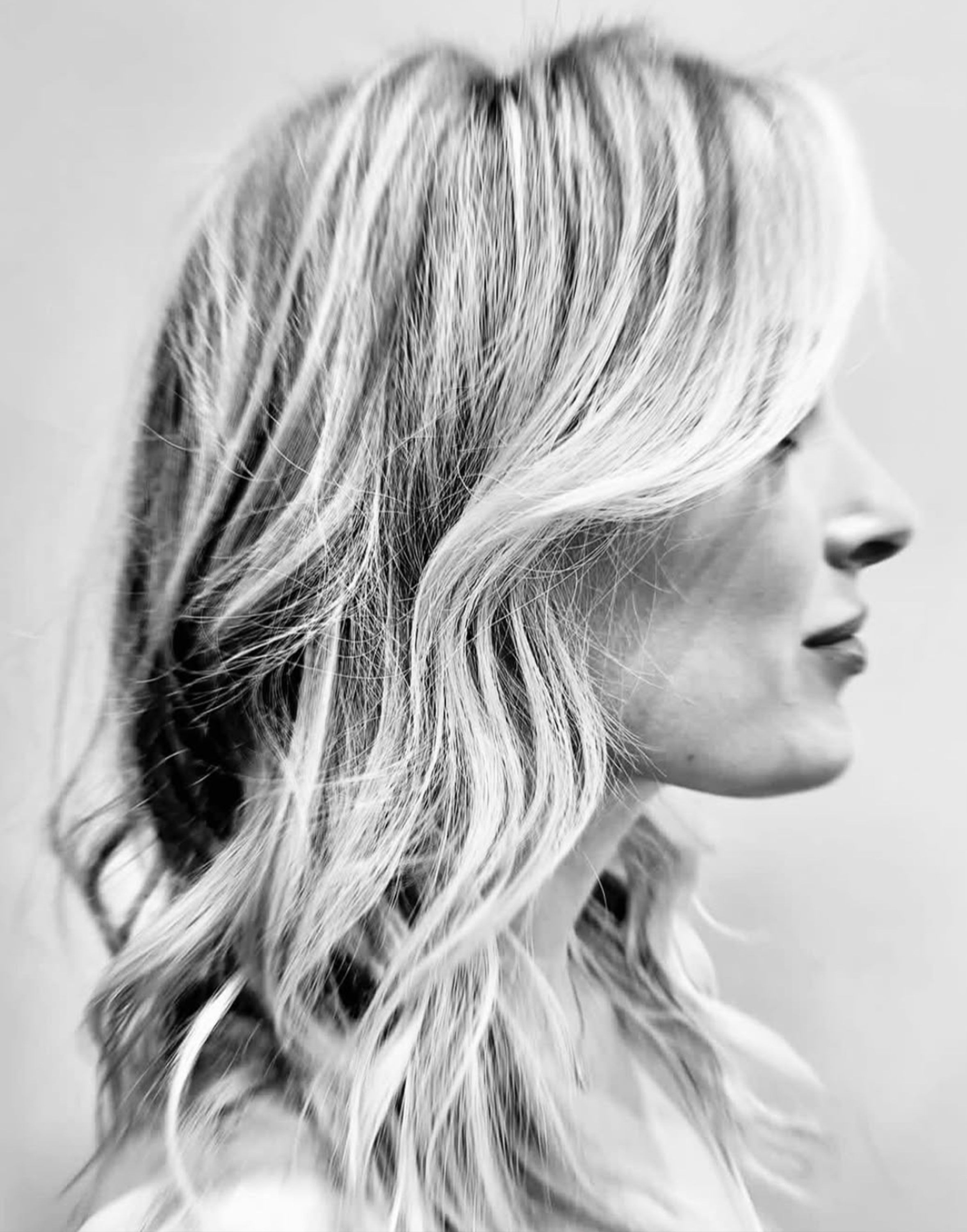 Soft blonde waves with face-framing layers, black-and-white profile.