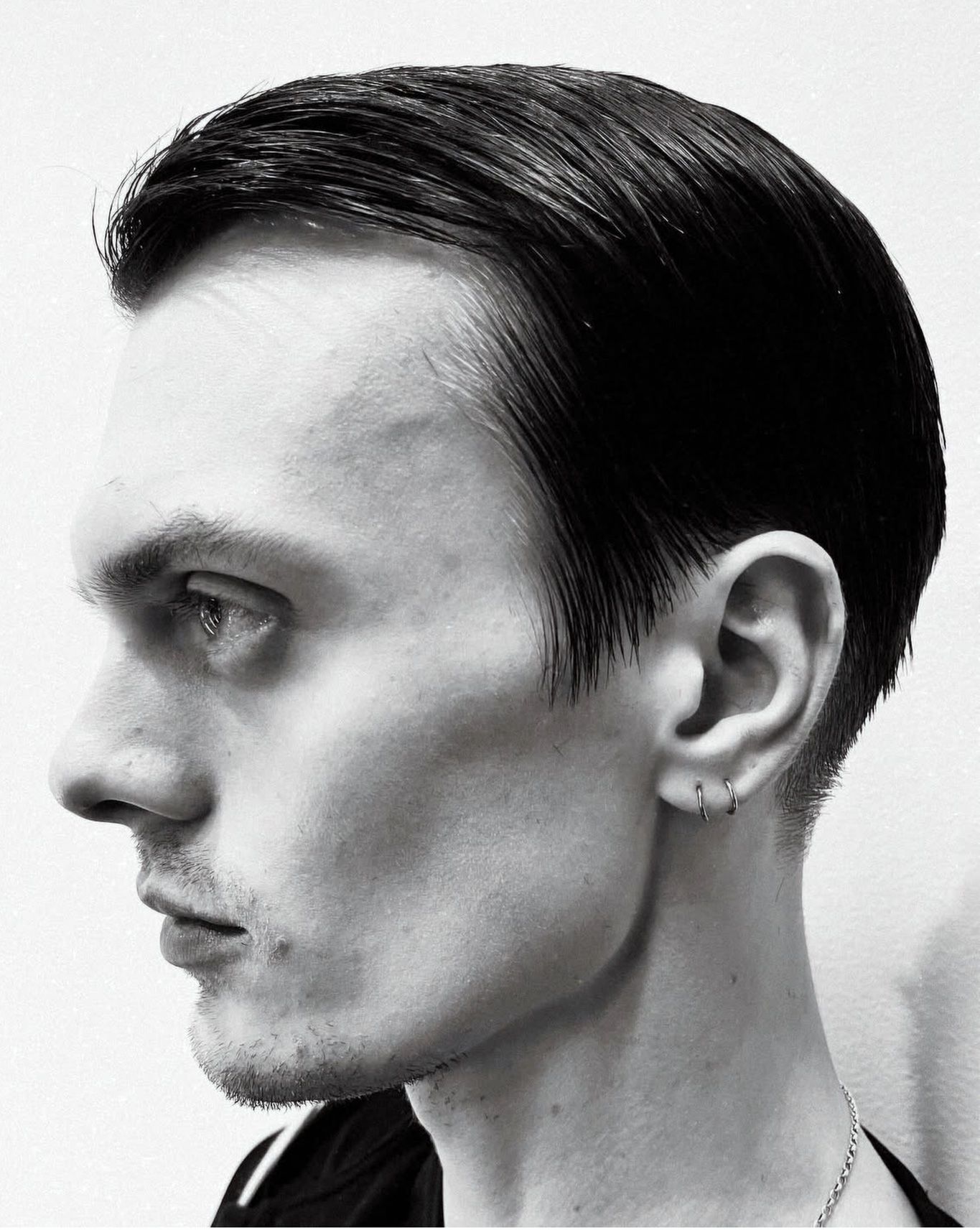 Slicked-back men’s cut, black-and-white profile.